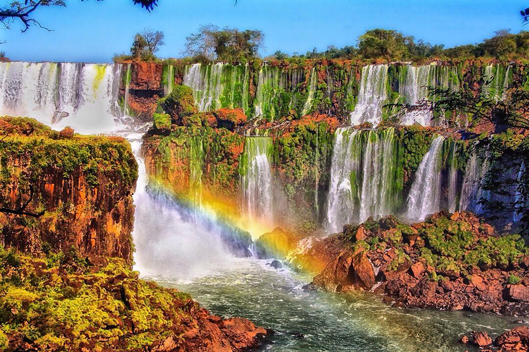 A rainbow forms at the bottom of a section of cascades at Iguazu Falls in Brazil. 
This was taken on the Brazilian side of the waterfalls, which offers broader panoramic views of the cascades. However, the Argentinian side provides the best access to the Devil’s Throat as well as many other parts of the park. Approximately 80% of the falls lie within Argentina with the remaining 20% in Brazil. The Argentinian side offers the best opportunities to get up close and among the waterfalls – particularly the Devil’s Throat sections.

Iguazu is not the biggest waterfall in the world by any measurement be it width (Khone Phapheng Falls in Laos), height (Victoria in Zimbabwe and Zambia) or flow rate (Boyoma Falls in Congo). However, its trans-border setting between Brazil and Argentina transport hubs and excellent walkway systems make it one of the most accessible in the world.

As waterfalls go, only Niagara Falls in the USA receives more visitors per year than Iguazu. When visiting Iguazu, the then US First Lady Eleanor Roosevelt reportedly exclaimed “Poor Niagara!” At just 50 meters (165ft), Niagara is a third shorter than Iguazu.

#IguazuFalls #Argentina #Brazil #travel #Iguazu #Brasil #amazing #waterfall #travelphotography #lp #SouthAmerica #Misiones #iguazuenconcierto #cataratas #falls #ig_worldclub #DiscoverEarth #master_shots #awesomeearth #wonderful_places