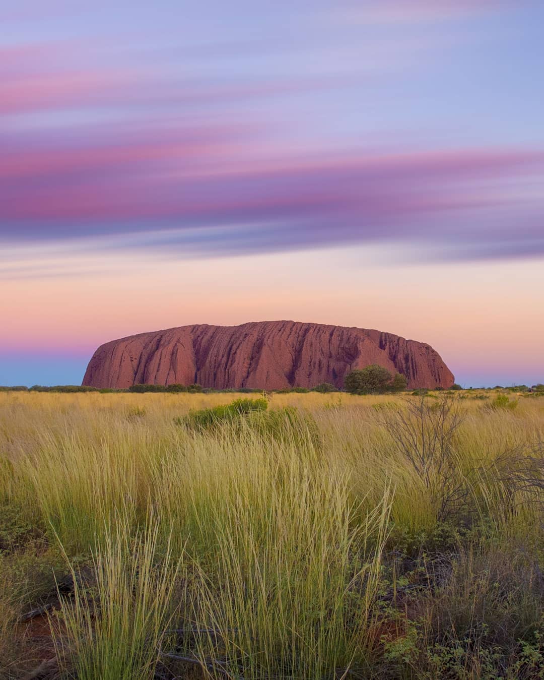 Watching the sun set and clouds cross the horizon above #Uluru in the @ausoutbacknt, arguably the most famous sight in all of Oceania. @australia's Red Centre has been named by @lonelyplanet as number 4 in its #BestinTravel regions of 2019. ⠀
⠀
Travel writer Bill Bryson described Uluru as strangely familiar and we felt the same way. Here was the rock we had seen in movies, postcards and documentaries, a rock that symbolised past conflict and enduring pain, a rock held sacred by Australia’s indigenous people.⠀
⠀
We watched it change colour for what felt like an age. Time well spent. ⠀
-⠀⠀
-⠀⠀
-⠀⠀
-⠀⠀
-⠀⠀
-⠀⠀
#Australia #seeaustralia #Uluru #exploreuluru #ayersrock #ulurukatatjutanationalpark #ulurusunrise #ulurusunset #visituluru #visitaustralia #northernterritory #visitnorthernterritory #ntaustralia #northernterritoryaustralia #katatjuta #alicesprings #therocktour #theoutback #outback #outbackaustralia #takeahike #travelawesome #lpPathfinders #exploreuluru #NTaustralia #redcentre @therocktournt