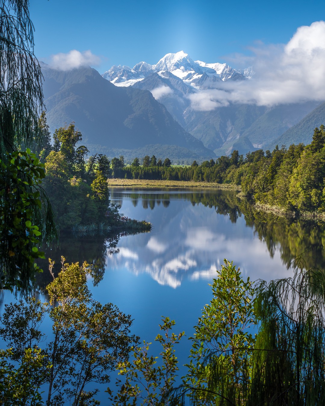 Looking across the still waters of Lake Matheson at New Zealand's highest and second highest mountains, Aoraki/Mount Cook and Mount Tasman, during our tour of the South Island with @gadventures  and @lonelyplanet.⠀
⠀
The gentle hike around Lake Matheson boasts some of the most serene vistas we've ever seen with the Southern Alps majestically reflected in the tranquil waters of the lake. ⠀
-⠀⠀
-⠀⠀
-⠀⠀
-⠀⠀
-⠀⠀
-⠀⠀
#Aoraki #MountCook #mountcooknz #MountTasman #MtCook #SouthernAlps #Matheson #LakeMatheson #FranzJosef #foxglacier #mountcooknationalpark #southislandnewzealand #southisland #southislandnz #newzealand #NZMustDo #RealMiddleEarth #NZ #visitnewzealand #lppathfinders #gadventures #liveoutdoors #bestintravel #thegreatoutdoors #wellhiked #takeahike #hikingadventures #getoutstayout #ig_newzealand #purenewzealand